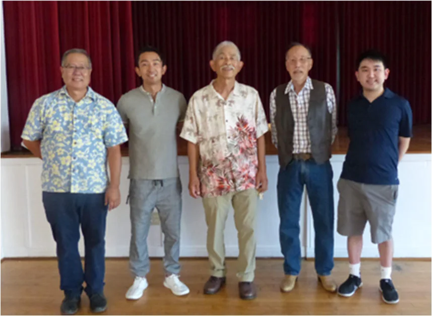 Five attendees from different generations stand together in the Social Hall during HJCI’s seventy-fifth anniversary gathering.