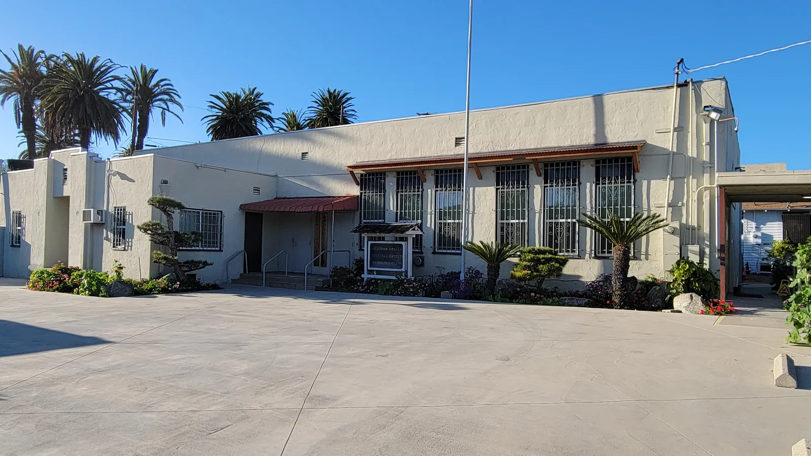 Exterior of the Hollywood Japanese Cultural Institute, with its entrance, landscaped driveway, and palm trees.