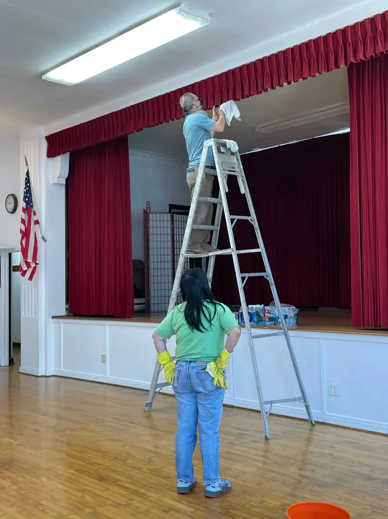 People caring for the stage area inside the HJCI Social Hall.